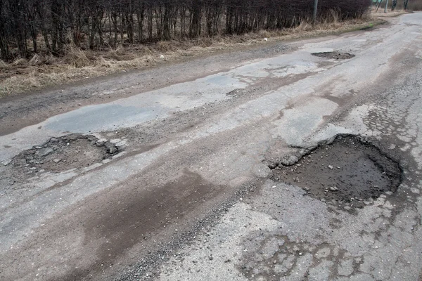 Estrada de asfalto danificada após o inverno. — Fotografia de Stock