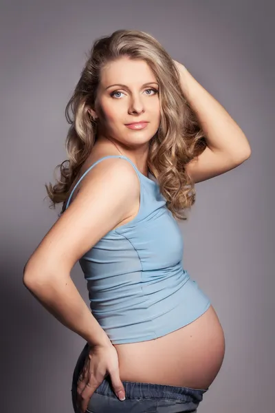Donna incinta guardando la fotocamera, una mano in alto — Foto Stock