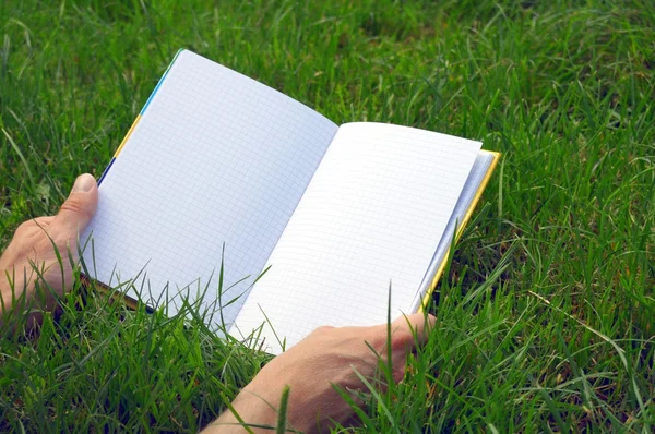 Otworzył książkę na trawie — Zdjęcie stockowe