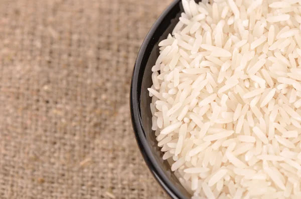 Niegotowane ryż w misce ceramiczne na juty Hesji backgrou — Zdjęcie stockowe