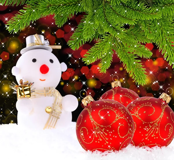 Homem de neve com bolas de Natal de vidro vermelho e pelos ramos de p — Fotografia de Stock