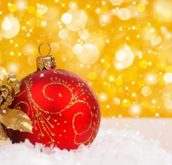 Červená vánoční koule na zlaté pozadí s prostorem pro text — Stock fotografie