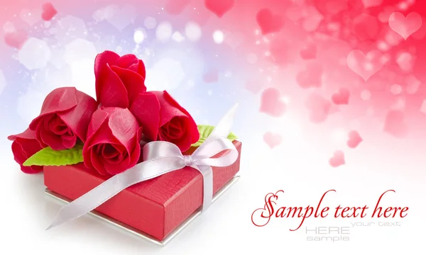 Little red gift with roses on festive background — Stock Photo, Image