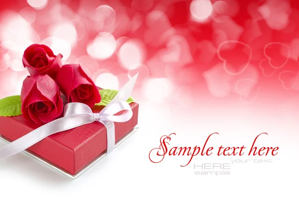 Kleines rotes Geschenk mit Rosen auf festlichem Hintergrund — Stockfoto