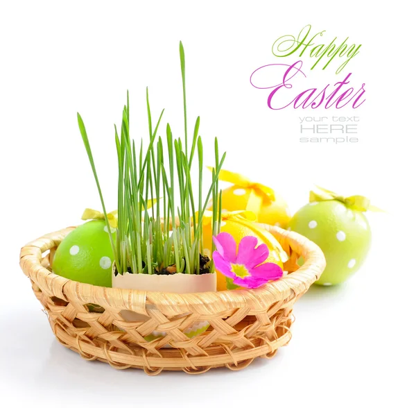 Beyaz zemin üzerinde bir sepet içinde Paskalya yumurtaları ve yeşil lahanası vardır — Stok fotoğraf