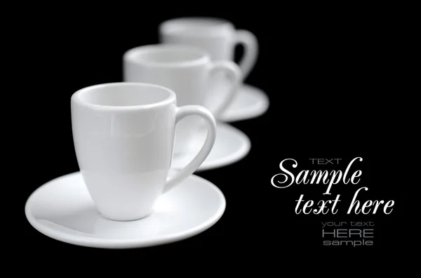 Пустые белые кофейные чашки и тарелки на черном фоне — стоковое фото