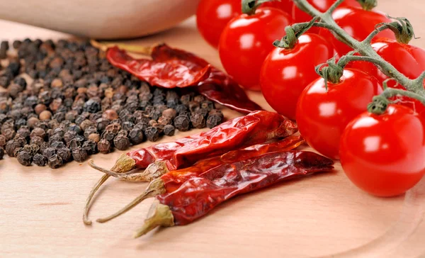 Tomates e pimentas em tábua de madeira — Fotografia de Stock