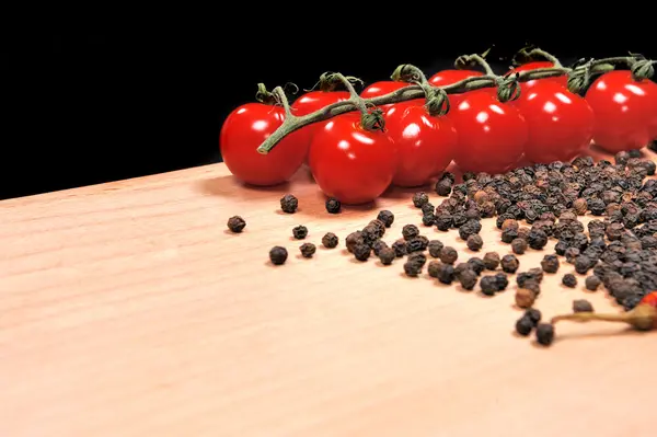 Tomates e pimentas em tábua de madeira — Fotografia de Stock