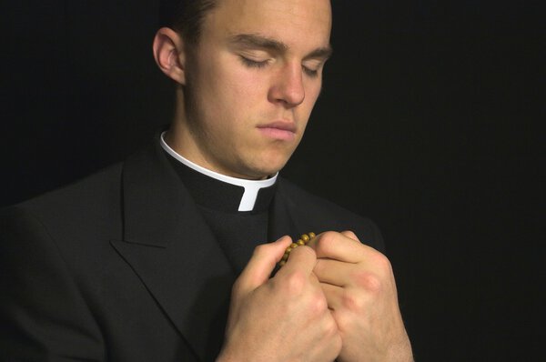 Молодой священник молится
