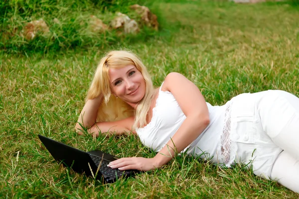 Νέοι όμορφη γυναίκα που εργάζεται με το laptop στο καταπράσινο γρασίδι — Φωτογραφία Αρχείου