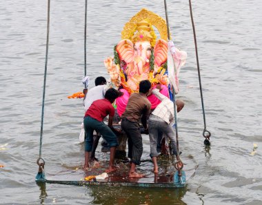 Ganesha idol lifted by crane for immersion clipart