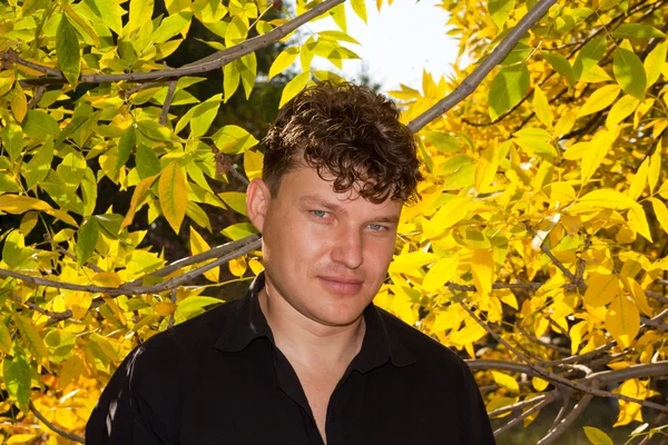 Man in een zwart shirt op de achtergrond van de herfst — Stockfoto