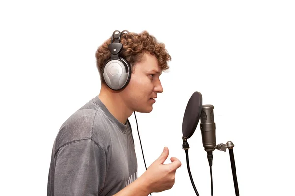 Mann mit Kopfhörer singt in ein Mikrofon auf weißem Hintergrund — Stockfoto