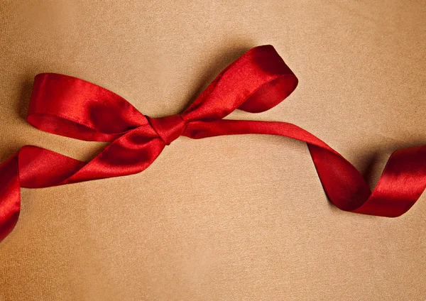Shiny red satin ribbon on golden background with copy space — Stock Photo, Image