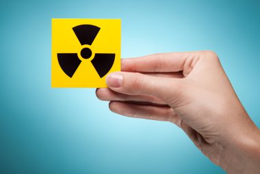 Woman's hand holding symbol - radiation. Against blue background clipart