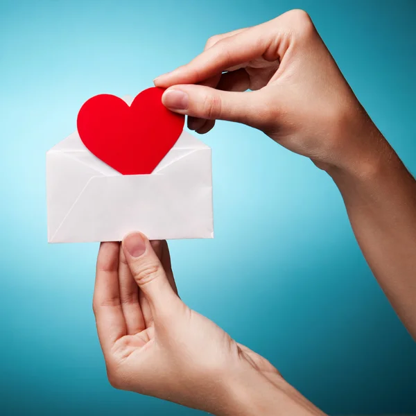 La main de la femme tenant une enveloppe avec un signe du cœur recommence — Photo