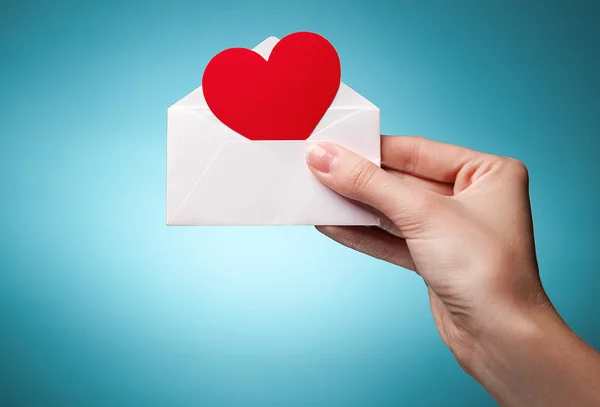 La main de la femme tenant une enveloppe avec un signe du cœur recommence — Photo