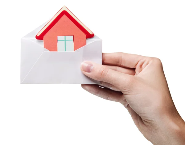 Woman's hand holding an envelope with a sign of the house isolat — Stock Photo, Image
