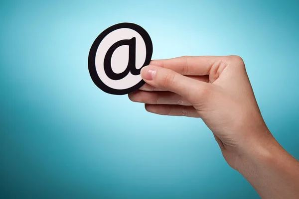 Main de femme tenant le signe de l'e-mail. Sur fond bleu — Photo