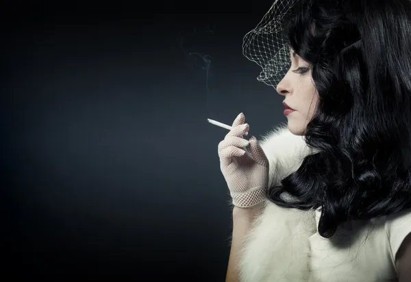 Femme rétro fumant sur fond sombre — Photo