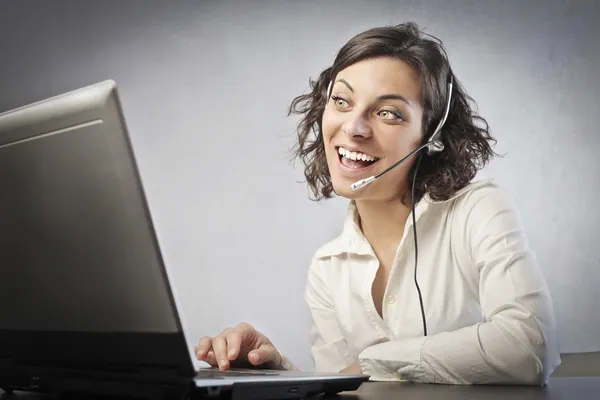 ノート パソコンの前に笑みを浮かべて女性オペレーター — ストック写真