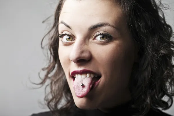 Dilini yapıştırma ve onun piercing gösteren güzel bir kadın — Stok fotoğraf
