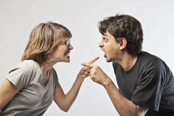 Жена и муж указывают пальцем друг на друга и ссорятся.
