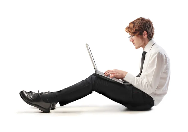 Isolated seated young businessman using a laptop — Stock Photo, Image