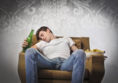 Young man sleeping on an armchair while holding a beer bottle and a bowl of chips clipart