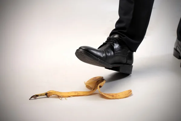 Fechar o pé de um homem prestes a escorregar em uma pele de banana — Fotografia de Stock