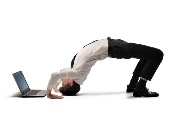 Jovem empresário fazendo acrobacias na frente de um laptop — Fotografia de Stock