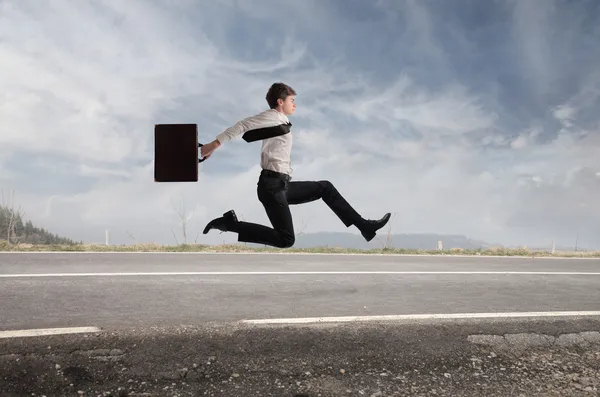 Joven hombre de negocios corriendo rápido en una carretera rural — Foto de Stock