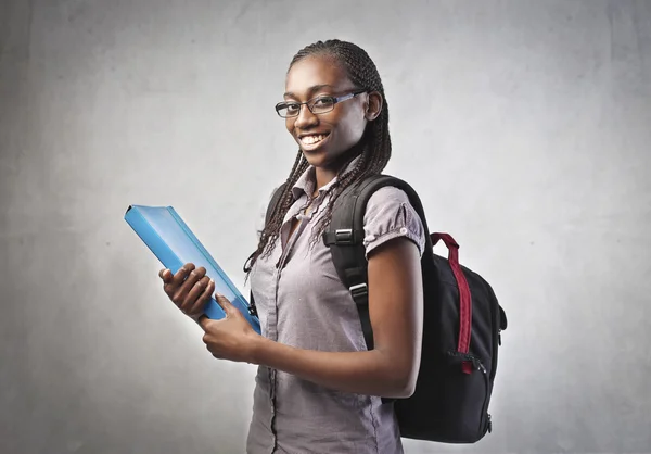 Улыбающийся африканский студент с рюкзаком и с папкой в руках — стоковое фото