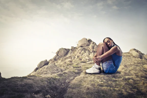 Νεαρή αφρικανική γυναίκα που κάθεται πάνω σε βράχο — Φωτογραφία Αρχείου