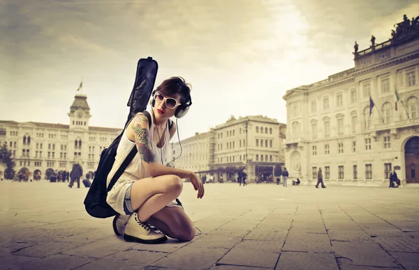 Hermosa joven en una plaza de la ciudad llevando una funda de guitarra sobre sus hombros —  Fotos de Stock