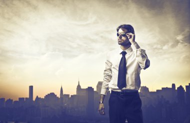 Portrait of a young businessman with skyline of a big city in the background clipart