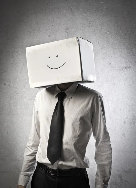 Jeune homme d'affaires portant un carton avec un visage souriant dessus — Photo