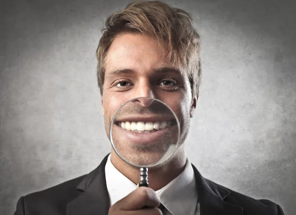 Νέος επιχειρηματίας περαστικών το χαμόγελό του με ένα μεγεθυντικό φακό — Φωτογραφία Αρχείου