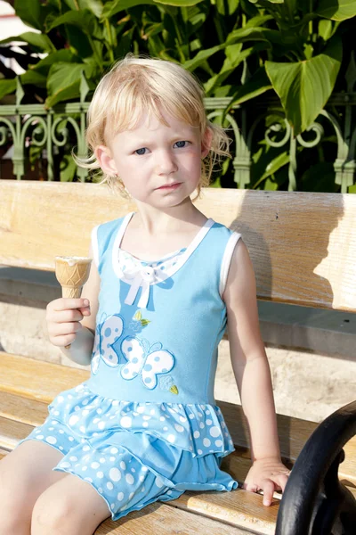 坐在长凳上的冰淇淋的小女孩 — 图库照片