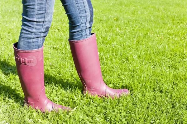 Detail of woman wearing rubber boots on lawn — Stock Photo, Image