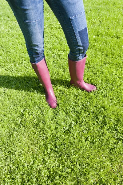 Detail of woman wearing rubber boots on lawn — Stock Photo, Image