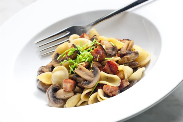 Pasta orecchiette with fried champignons and bacon — Stock Photo, Image