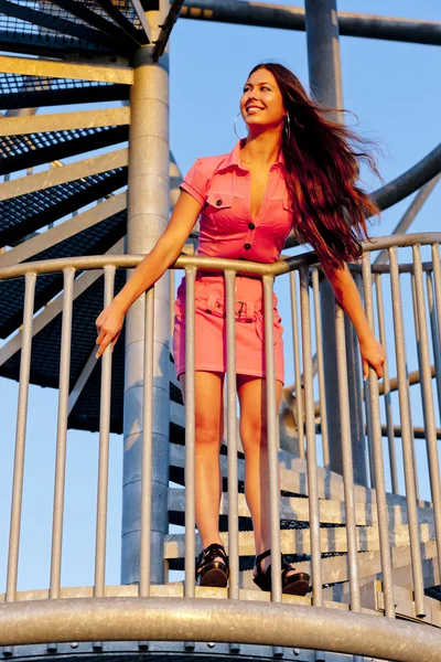 Ung kvinna som bär Rosa klänning stående på trappan på jakt fiberkabel — Stockfoto