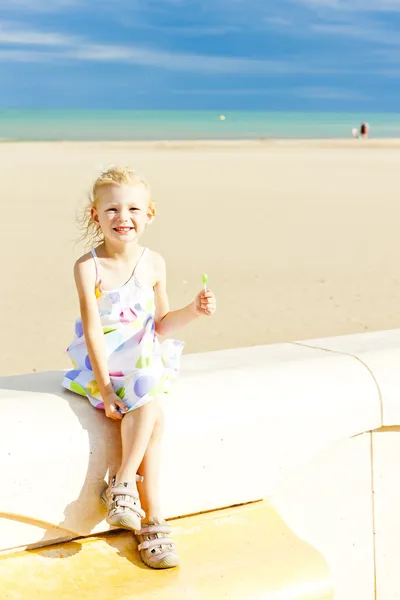 Menina com um pirulito na praia no mar — Fotografia de Stock