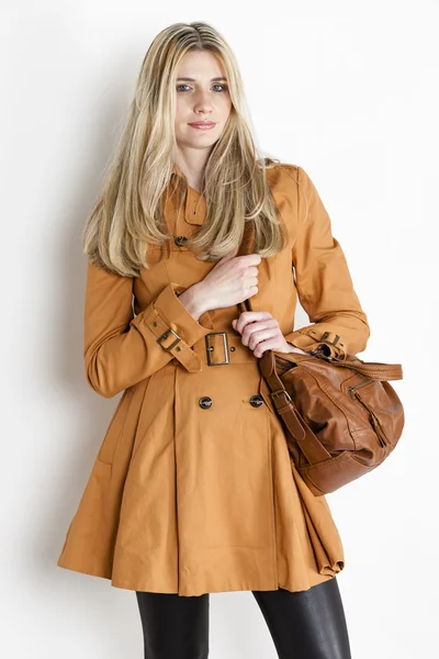 Портрет стоящей женщины в коричневом пальто с сумочкой — стоковое фото