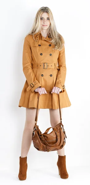 コートと、h とファッショナブルな茶色の靴を着て立っている女性 — ストック写真