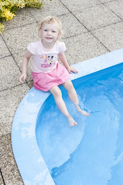 Kleines Mädchen sitzt am Swimmingpool — Stockfoto