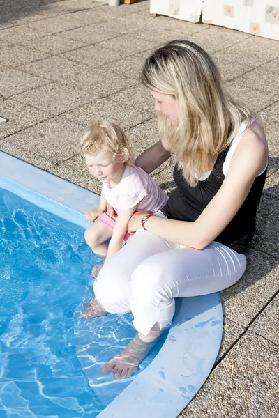 Anne ile kızını yüzme havuzunun kenarında oturan — Stok fotoğraf