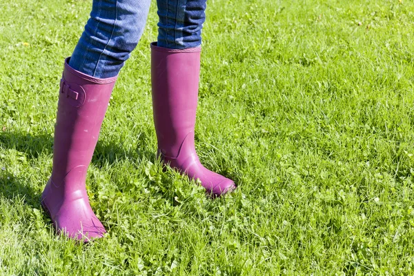 Çimlerde lastik çizme giyen bir kadın. — Stok fotoğraf