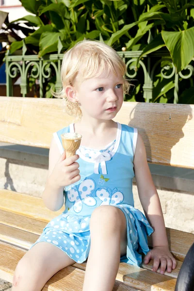 Маленька дівчинка з морозивом сидить на лавці — стокове фото